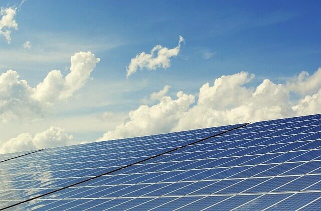 Des panneaux solaires sont visibles sous un ciel bleu ponctué de nuages.